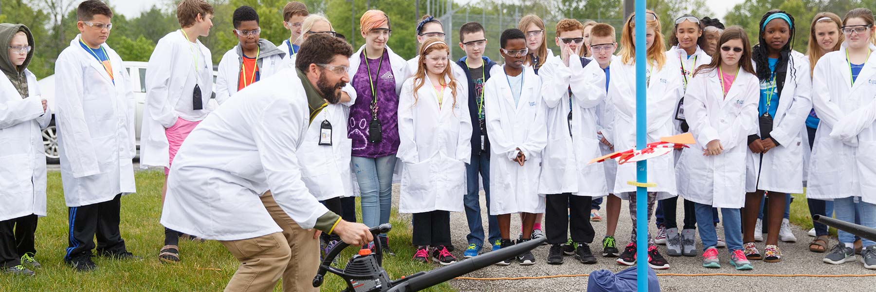 A scientist in a white lab coat performs an experiment for children.